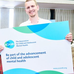 Dr Max Davie, Paediatrician, holding a sign about ACAMH