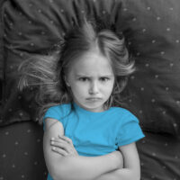 Angry,Child,Girl,Lying,On,The,Bed,With,Crossed,Hands