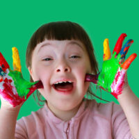 happy young girl painted hands up to face