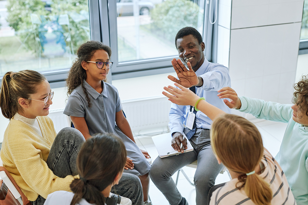 High angle view of teen high five with therapist while celebrating success in support group circle