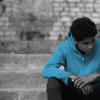 teen boy sitting on steps sad