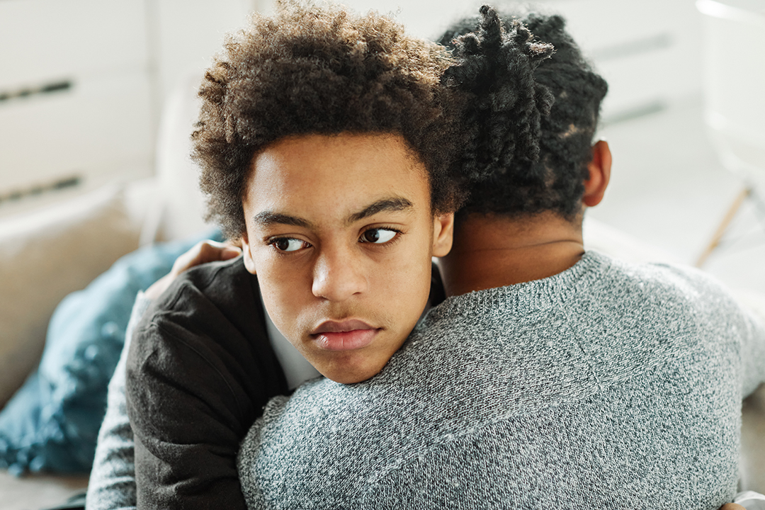 Portrait of son hugging his father, together at home. Son caring for his father, putting hand on his shoulder, comforting and consoling him. Family love, bonding, care and confidence