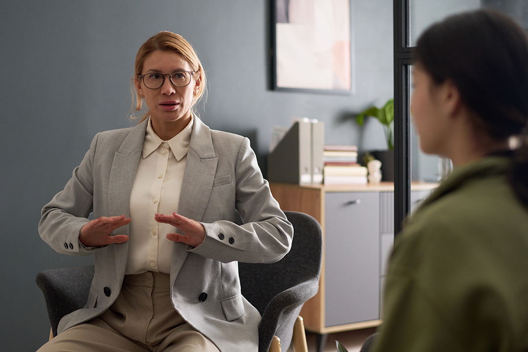 Portrait of mature female therapist guiding client through breathing exercise during mental health session