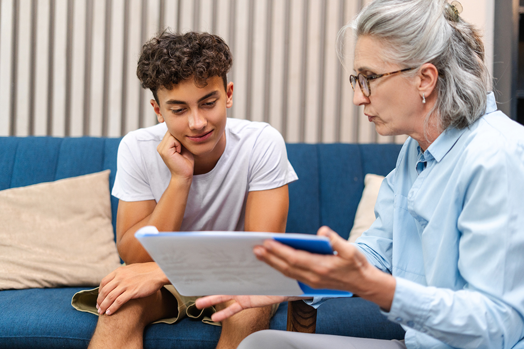 Teenage boy is listening attentively to his therapist while looking at a treatment plan during a therapy session at the psychologist's office