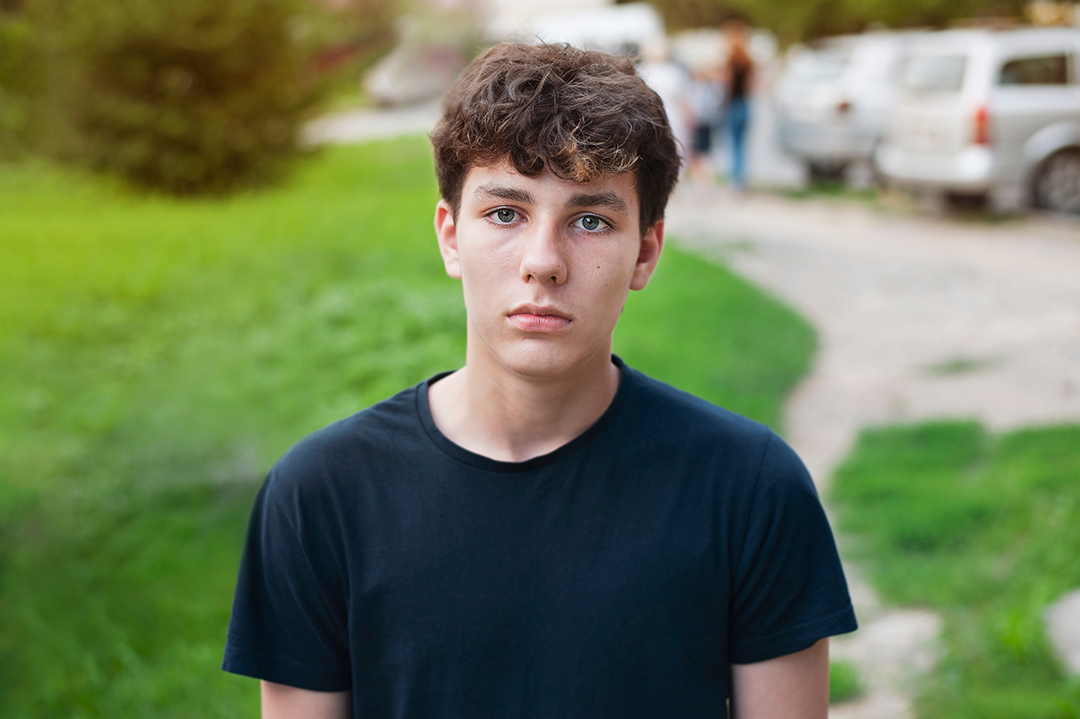 Young teenager boy is confused, dissatisfied, a little sad on the street, the concept of finding something new, new friends, feelings. Cute young sad guy in park