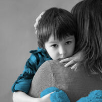 Sad little child, boy, hugging his mother at home, isolated image, copy space. Family concept