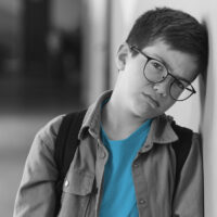 Traumatised boy leaning against wall very sad