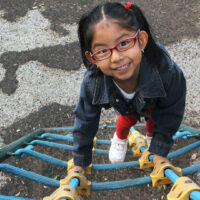 Latina brunette girl with eye glasses plays in the playgroud