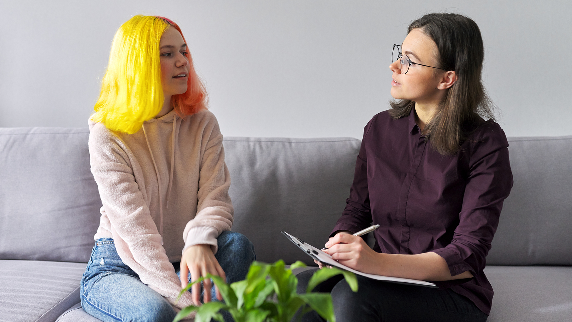 teen girl with bright yellow hair giving interview to female psychiatrist