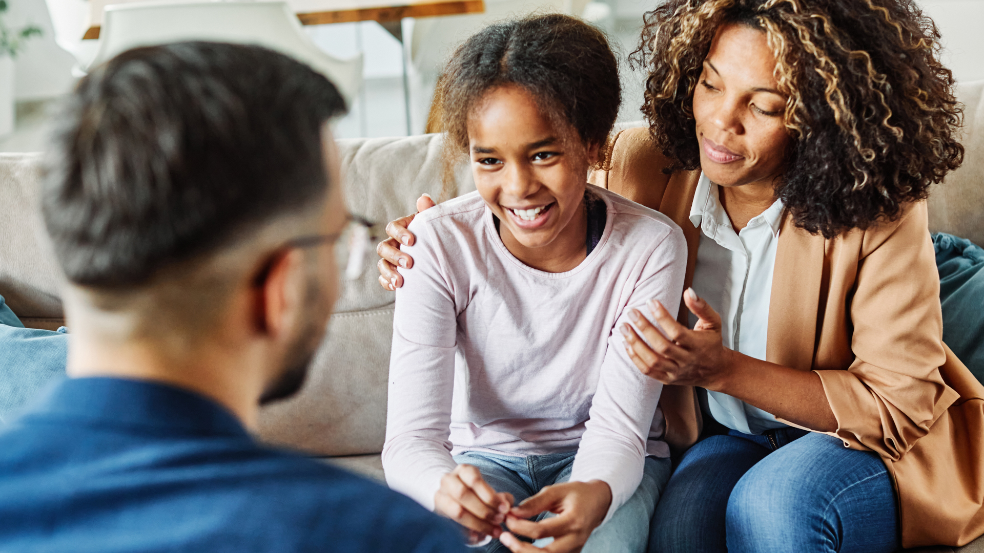 smiling young teen with mother talking to an adult male with back to camera