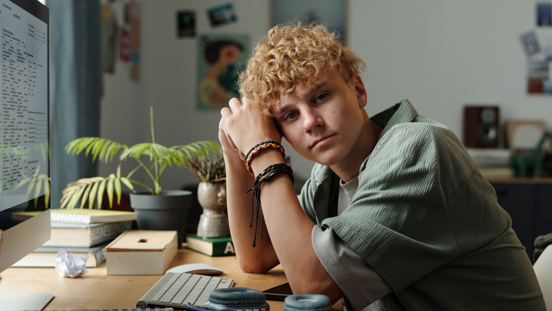 teenage boy sitting at desk leaning on arm