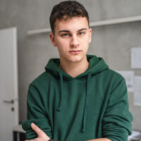 teenage boy stood in room at home wear green hoodie