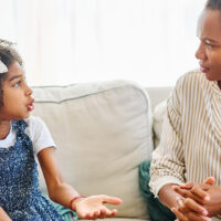 young girl sat on sofa psychologist discussing mental health
