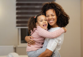 Portrait of happy mother and daughter hugging each other in bedroom at home