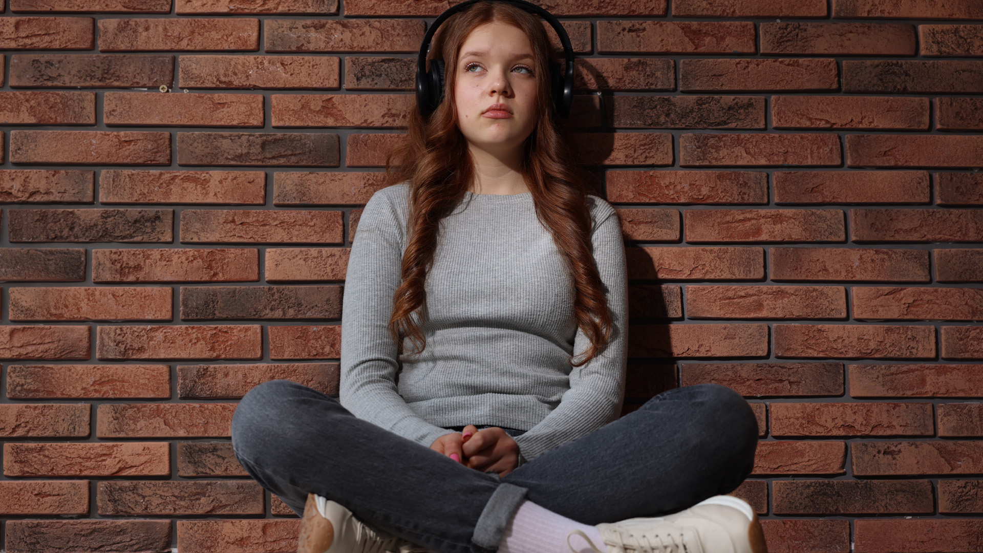 teenage girl with headphones listening to music near brick wall indoors teenage girl with headphones listening to music near brick wall indoors